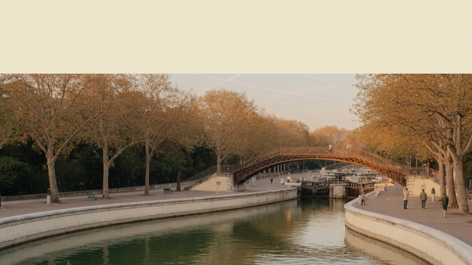 Golden hour light along a Paris canal with iron bridges